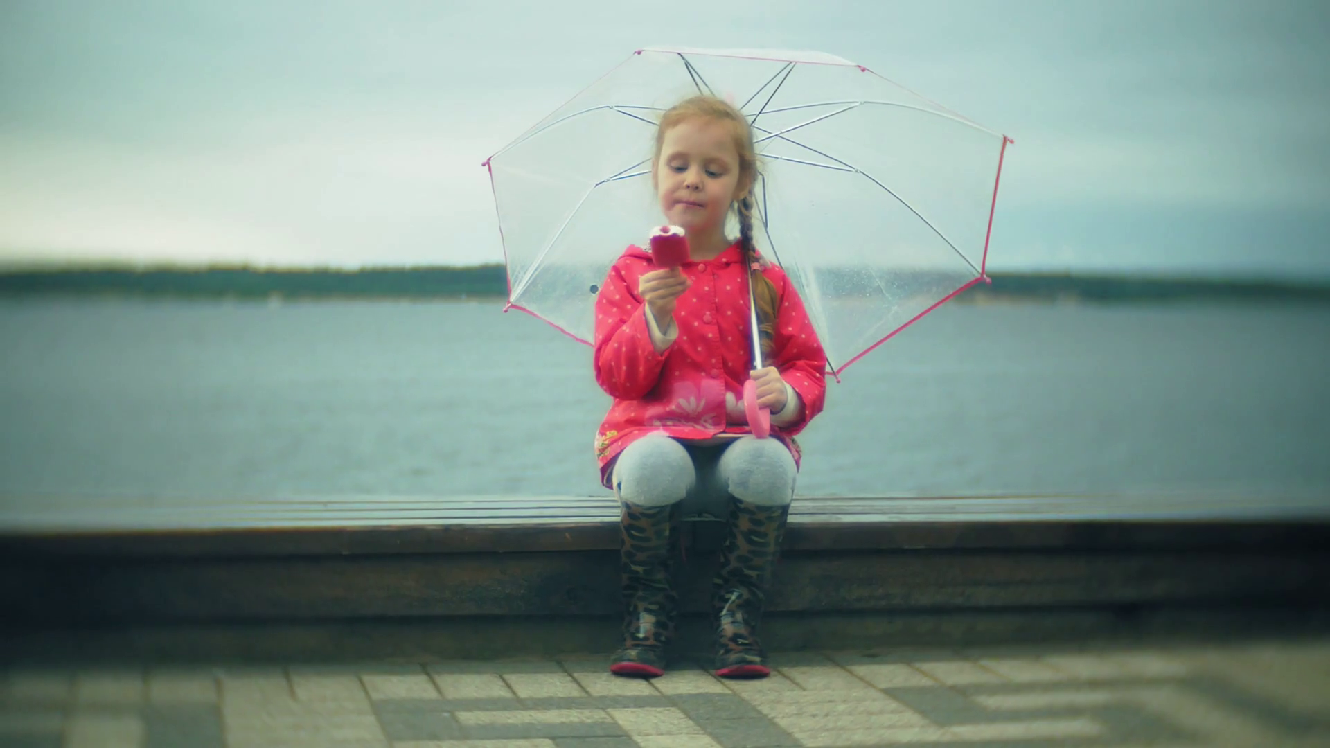 videoblocks little beautiful girl with umbrella playing in the rain eating ice cream on the coast smwkcg7hg7 thumbnail full01
